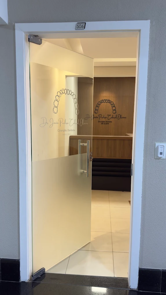 Entrada do consultório na sala 506, com porta de vidro e logotipo do Dr. João Pedro Cabral Olivier